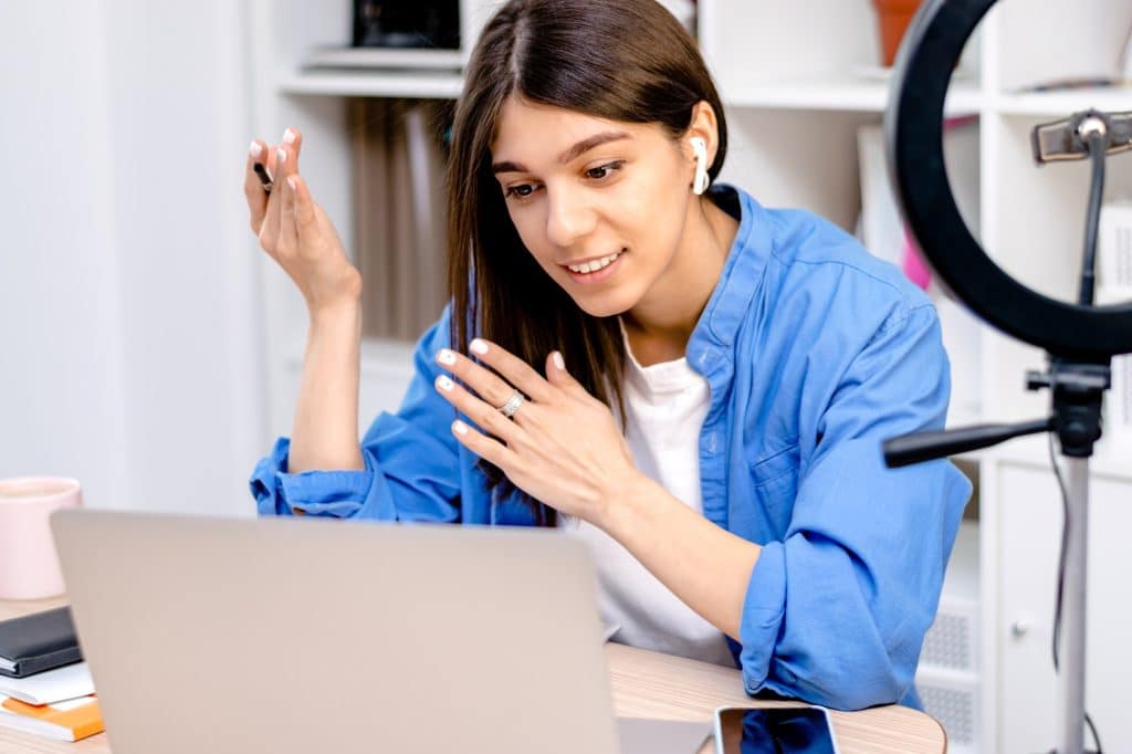 Girl blogger with earphones using laptop,chatting with followers in social network at home.