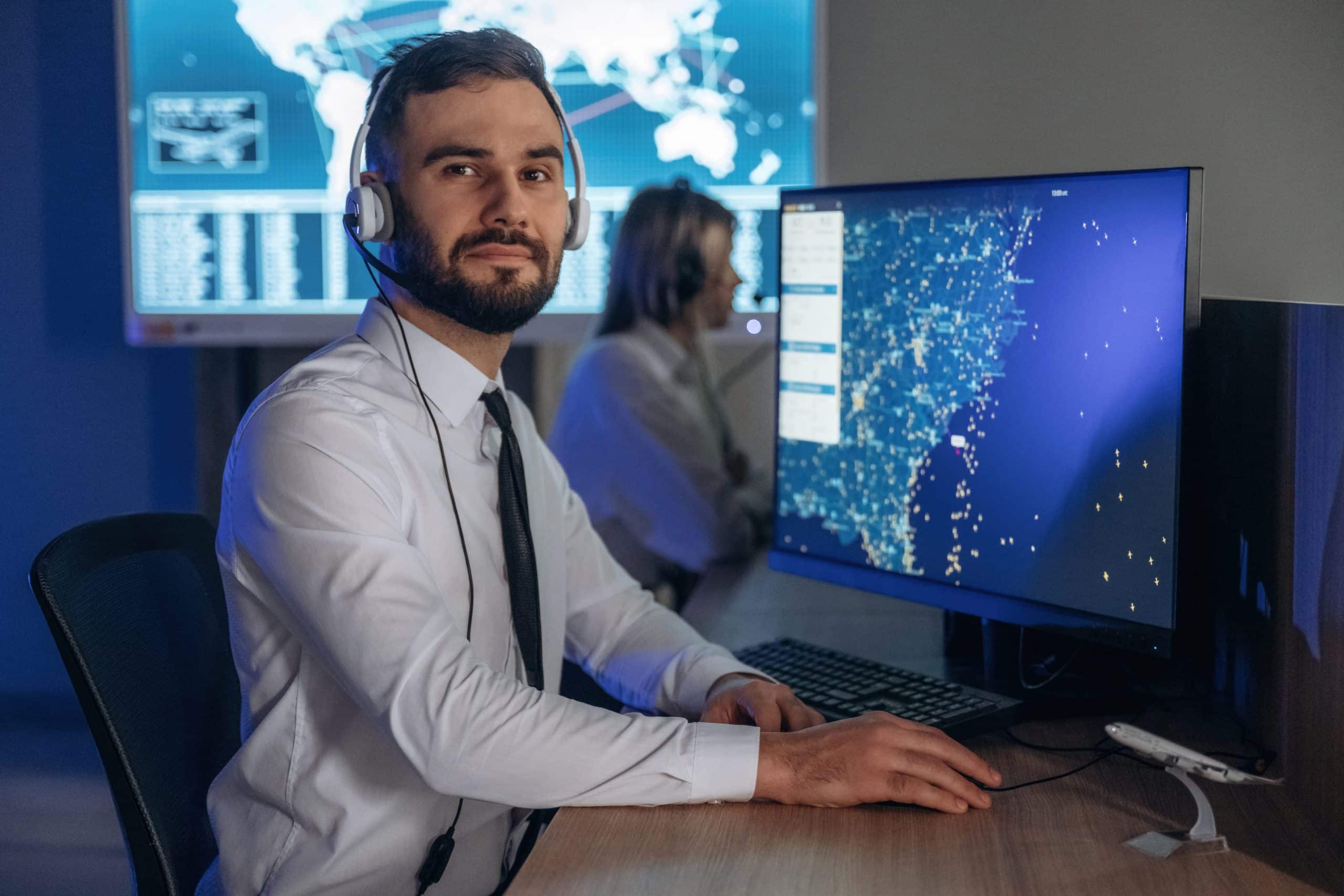 Looking at the camera. People are working by computers in airline company